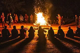 personas en un campamento de noche al lado de un fogon