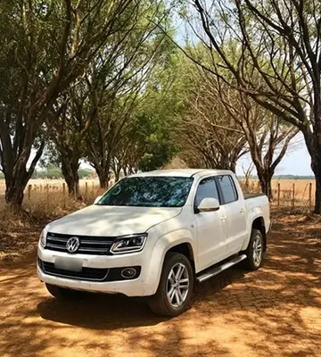 Camioneta amarok color blanco en camino de tierra rodeado de arboles